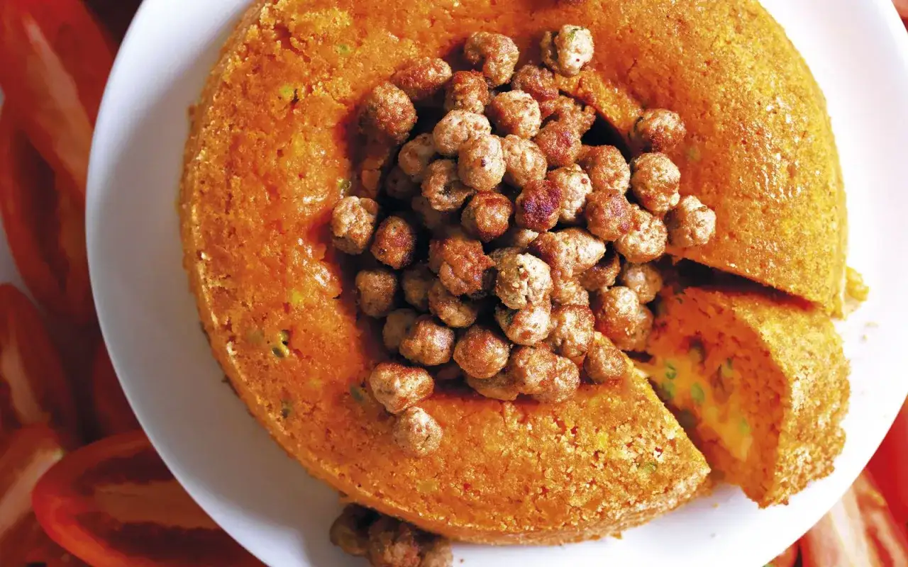 Sart&ugrave; di riso dorato, ripieno di piselli e formaggio, guarnito con polpettine.
