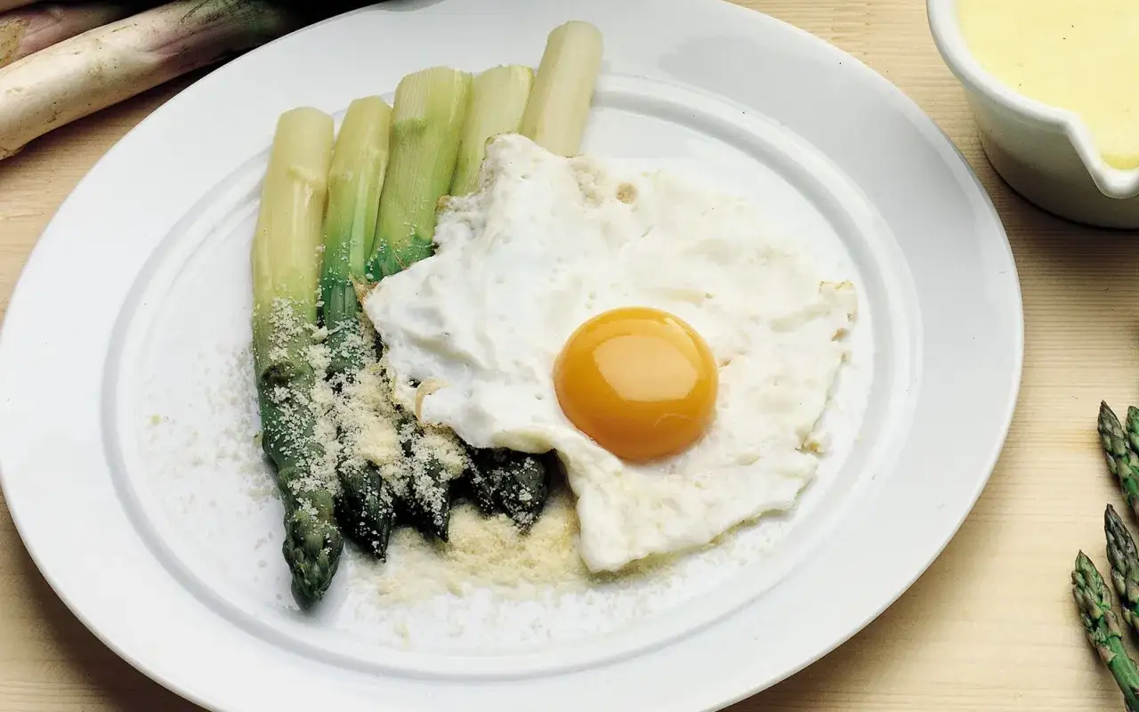 Asparagi alla Bismarck con uovo fritto e parmigiano grattugiato, un piatto semplice ma gustoso.