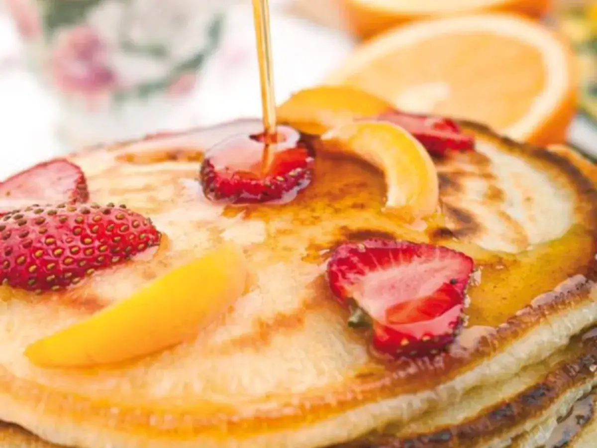 Pancake senza glutine con fragole, pesche e sciroppo d'acero. Un dolce delizioso e leggero per iniziare la giornata.