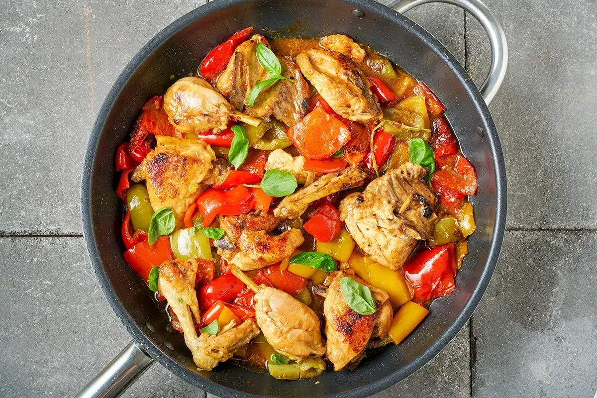 Fajitas di pollo succulente in padella con peperoni colorati e basilico fresco.