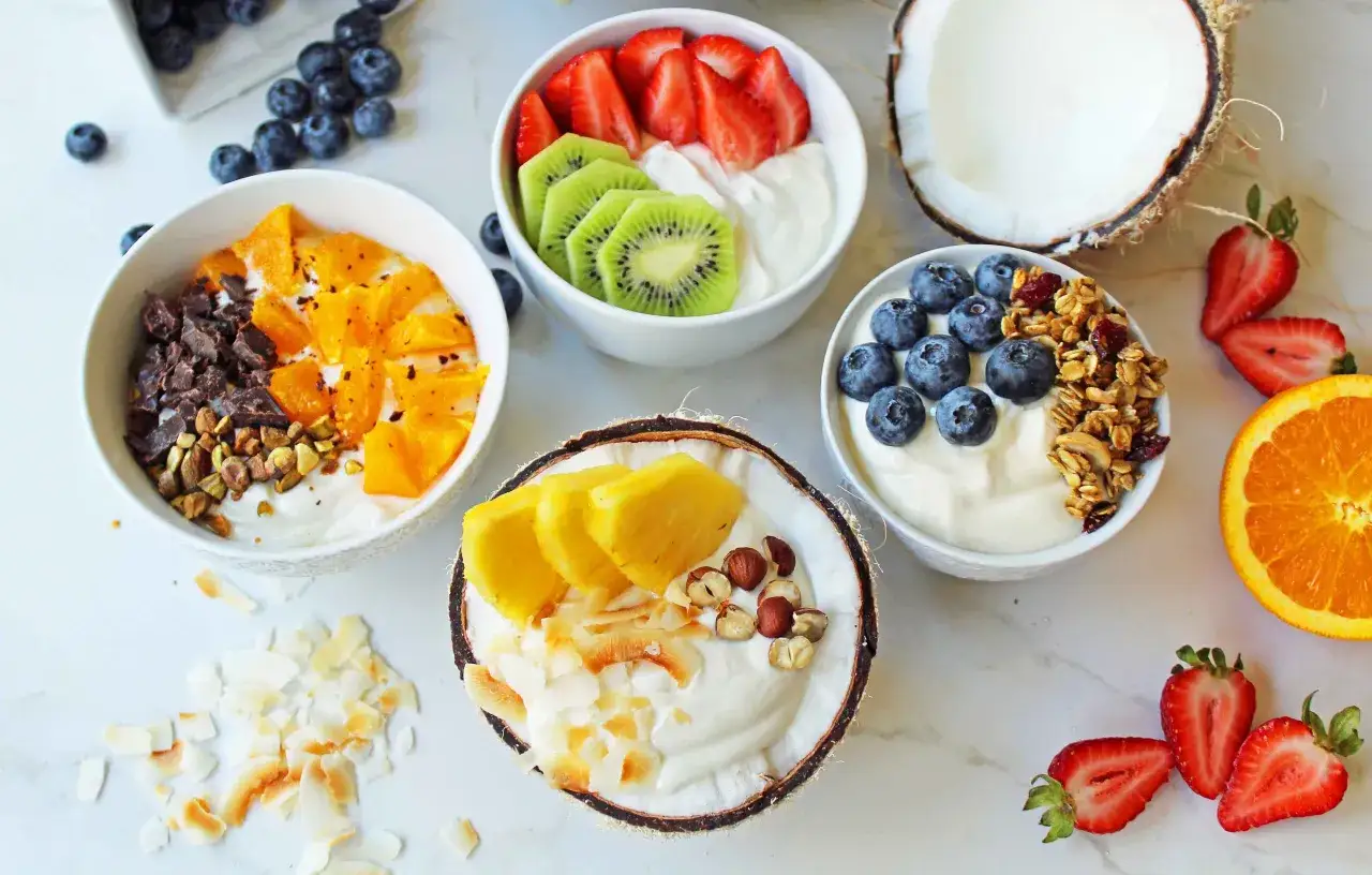 Deliziosa colazione con yogurt greco, fragole, kiwi, arancia, mirtilli, ananas, cocco e granola.