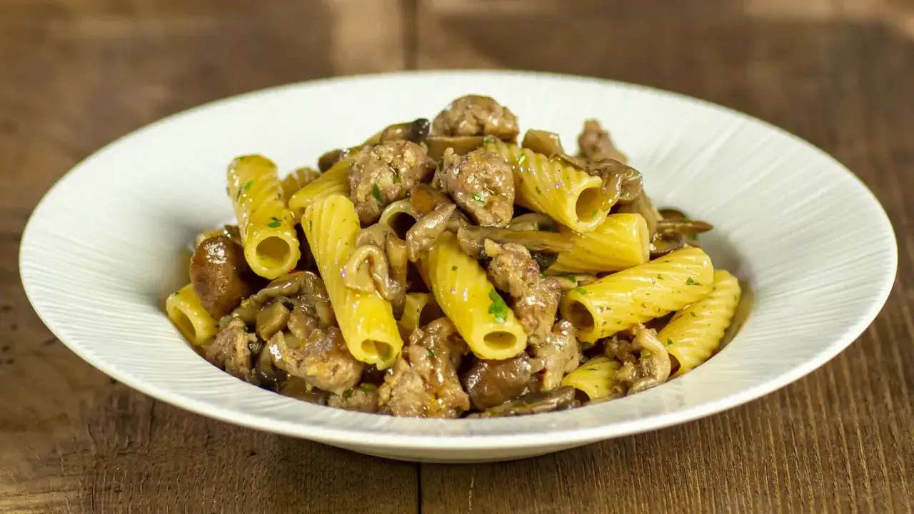 Piatto di pasta funghi e salsiccia, un classico saporito e confortante, pronto per essere gustato.