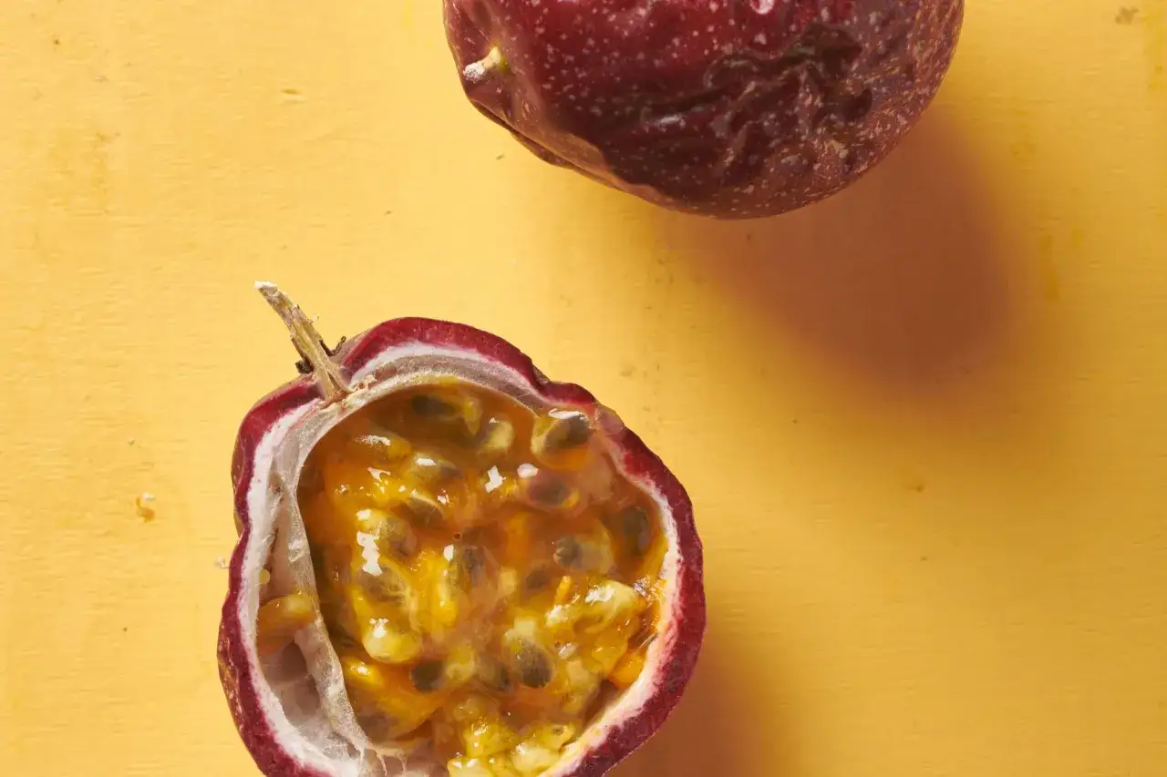 Un frutto della passione tagliato a met&agrave; rivela la sua polpa succosa e i semi scuri su sfondo giallo.