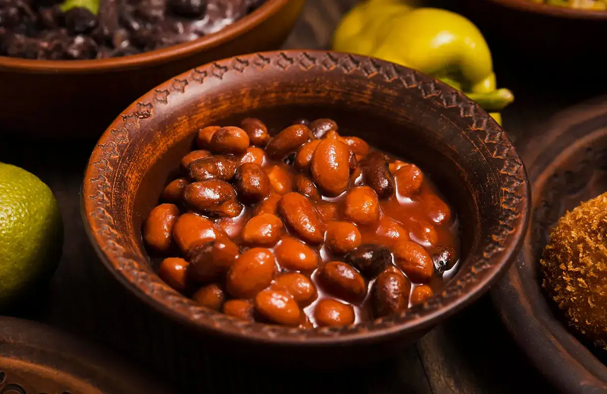 Fagioli borlotti in umido, pronti per la cottura. Accanto, lime e un peperone giallo.