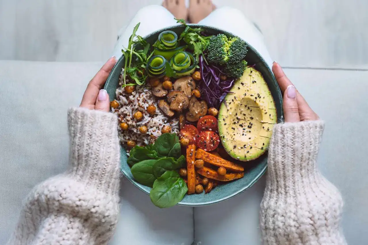 Una ciotola colorata con cibi senza carboidrati: avocado, verdure, ceci e riso integrale.
