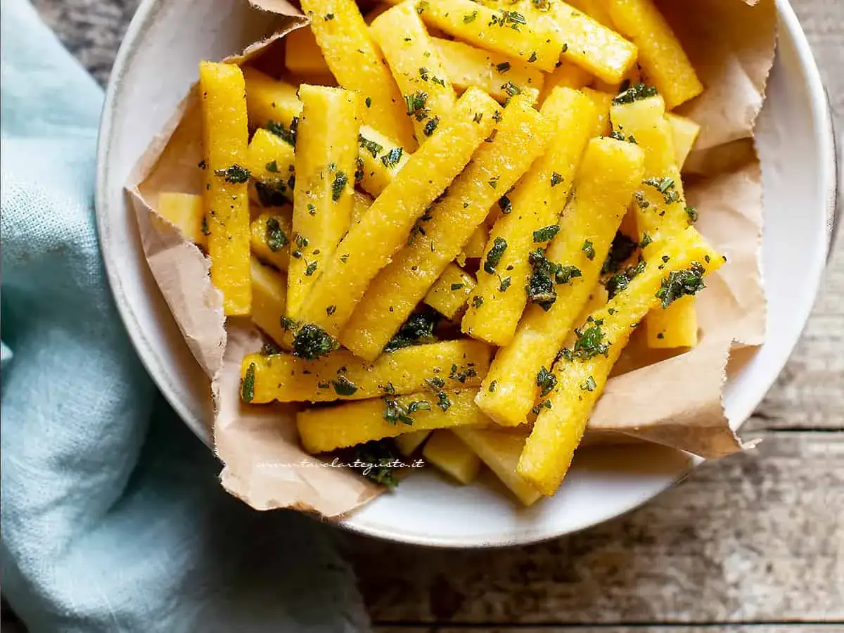 Bastoncini di polenta dorati, conditi con erbe aromatiche fresche. Perfetti come contorno o antipasto, ideali per scoprire polenta con cosa accompagnarla.