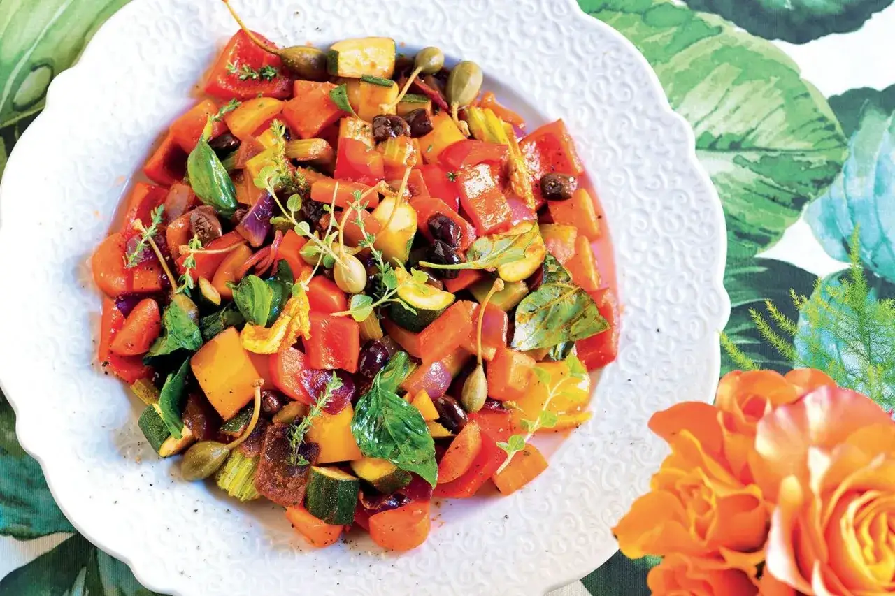 Un colorato mix di quali sono le verdure: peperoni, zucchine, carote e olive, guarnito con erbe aromatiche fresche.