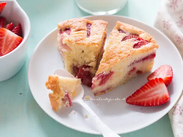 Fette di torta di fragole soffice e profumata, con fragole fresche e una cucchiaiata appena assaggiata.