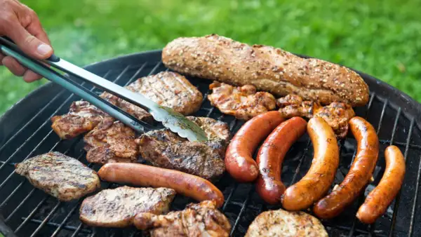 Grigliata con tante salsicce e bistecche, pane rustico e pollo. La carne da fare alla brace è pronta per essere gustata.