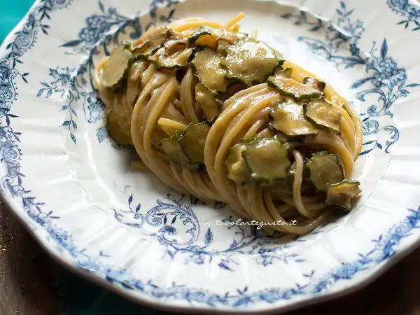 Spaghetti alla Nerano, un piatto cremoso con zucchine fresche, servito su un piatto decorato con motivi blu.