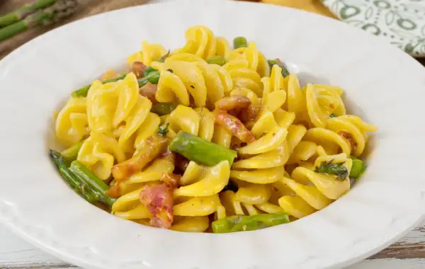 Fusilli cremosi con pancetta croccante e asparagi freschi, una deliziosa carbonara di asparagi.