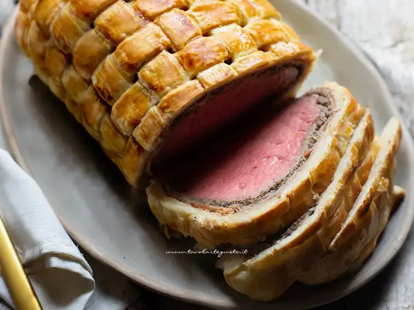 Un succulento filetto alla Wellington, cotto alla perfezione e avvolto in pasta sfoglia dorata, pronto per essere gustato.