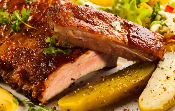 Succulente costine al forno, glassate e cotte alla perfezione, servite con cetriolini e insalata fresca.