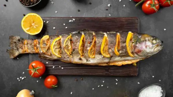 Trota al forno con fette di limone, pomodorini e sale grosso. Un piatto che ricorda i sapori del mare, ma che non appartiene ai crostacei quali sono.